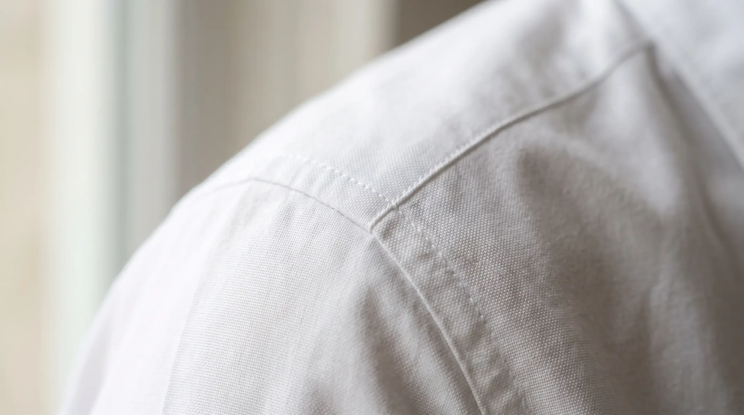 A detailed macro view highlighting clean, crisp shoulder seams and the opaque weave density of a premium cotton poplin shirt.