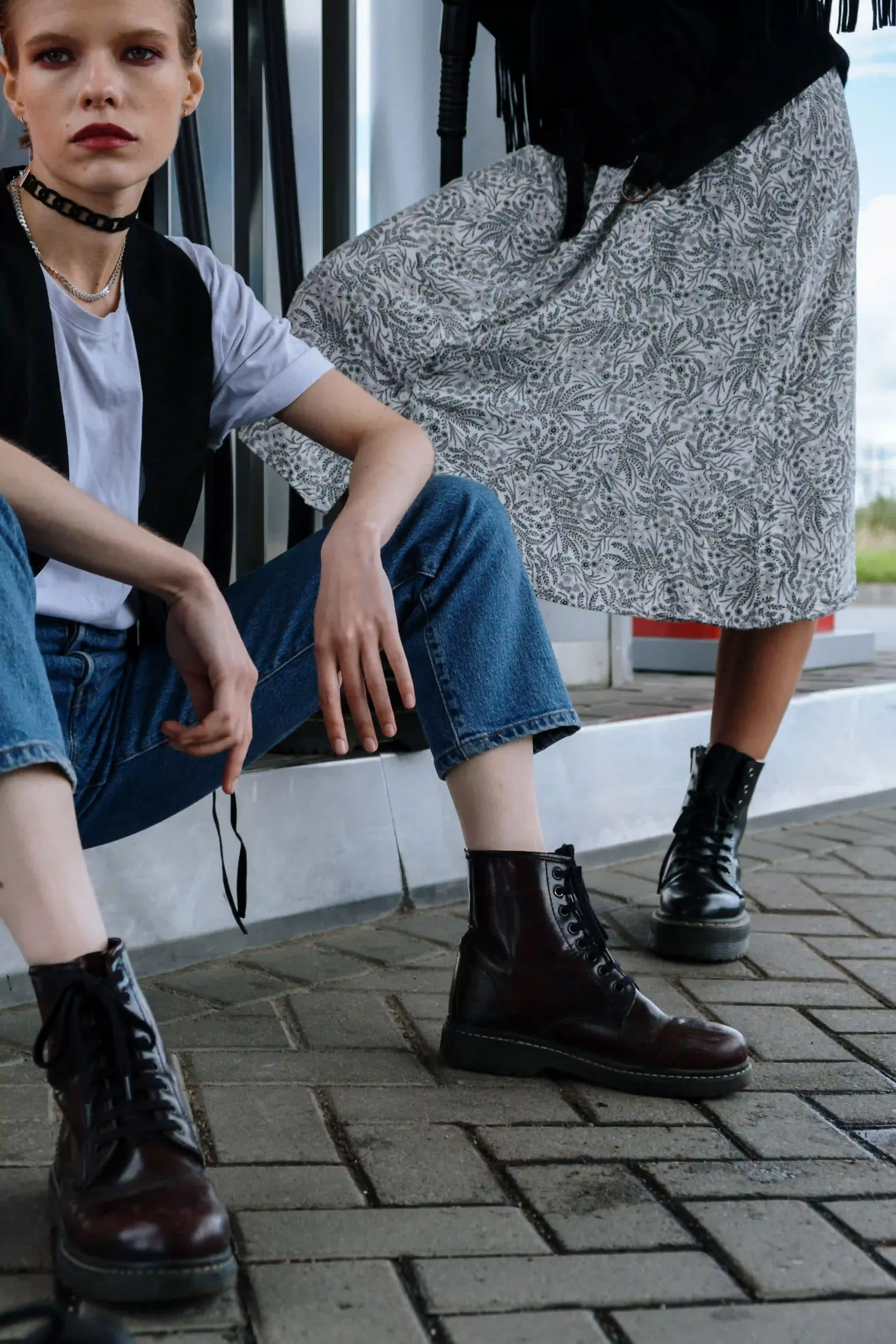 Woman in denim jeans and black leather ankle boots posing against a brick wall in an edgy street style look