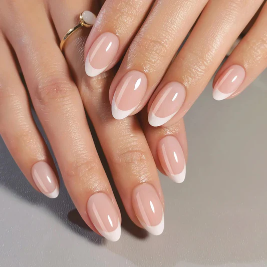 A hand with short round nails showing translucent milky white polish that lets the natural nail show through