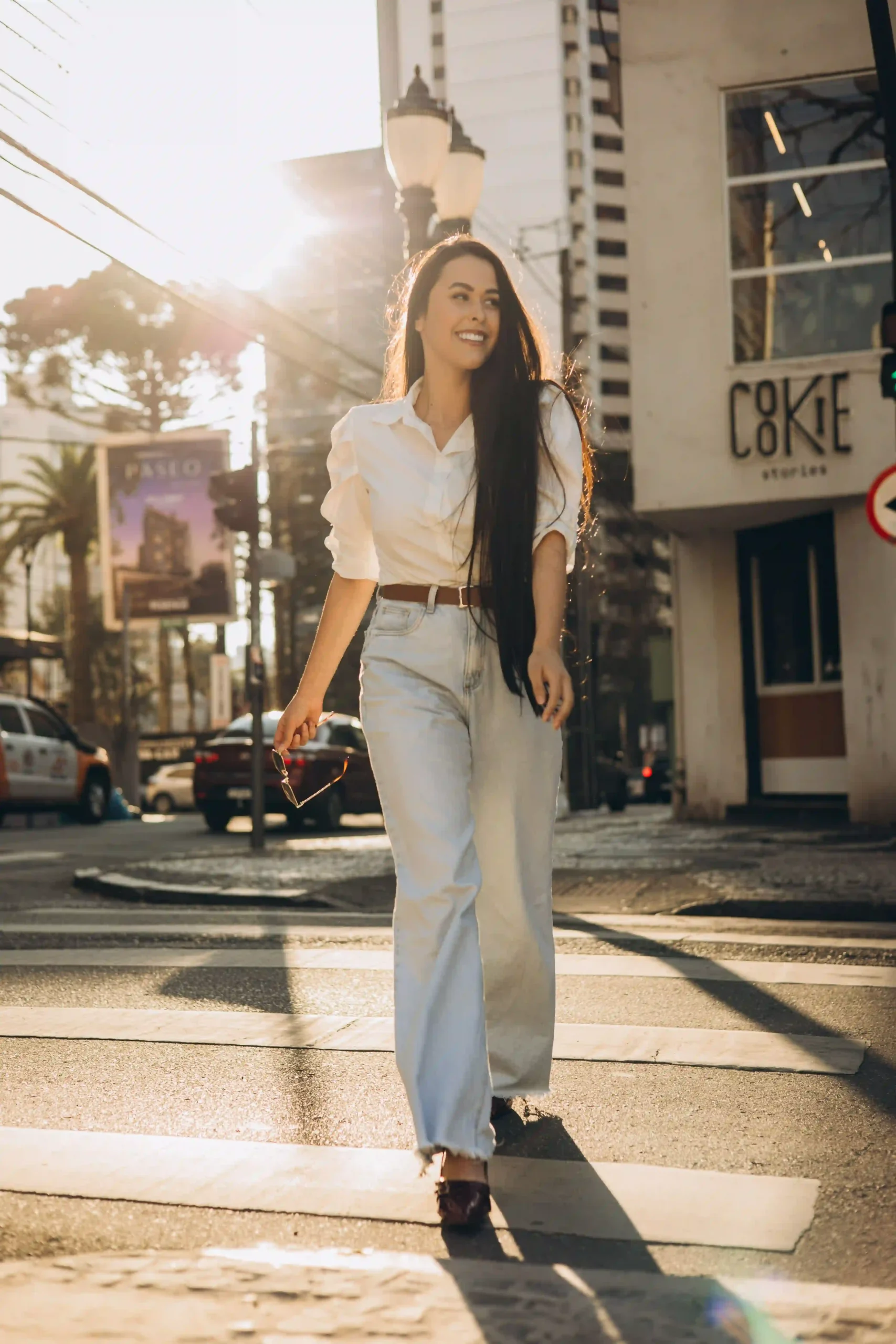 Woman walking on a city street in high-waisted blue jeans with a tucked-in white shirt