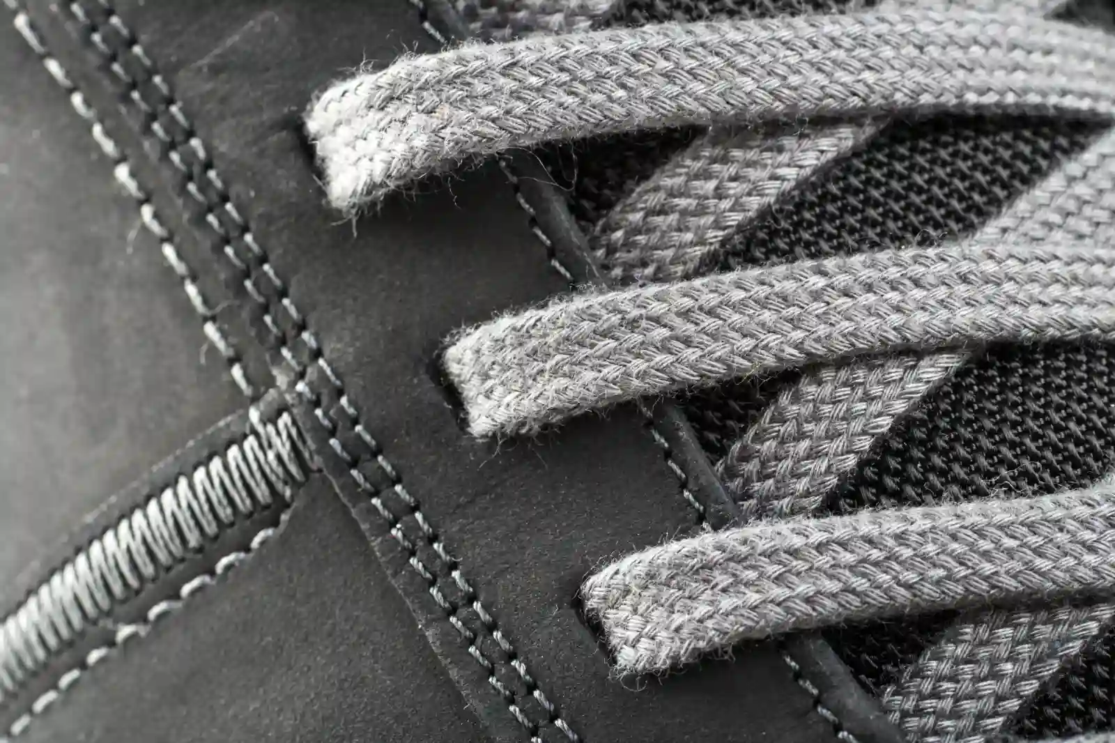 Macro view of even stitching and a lace on a gray sneaker panel