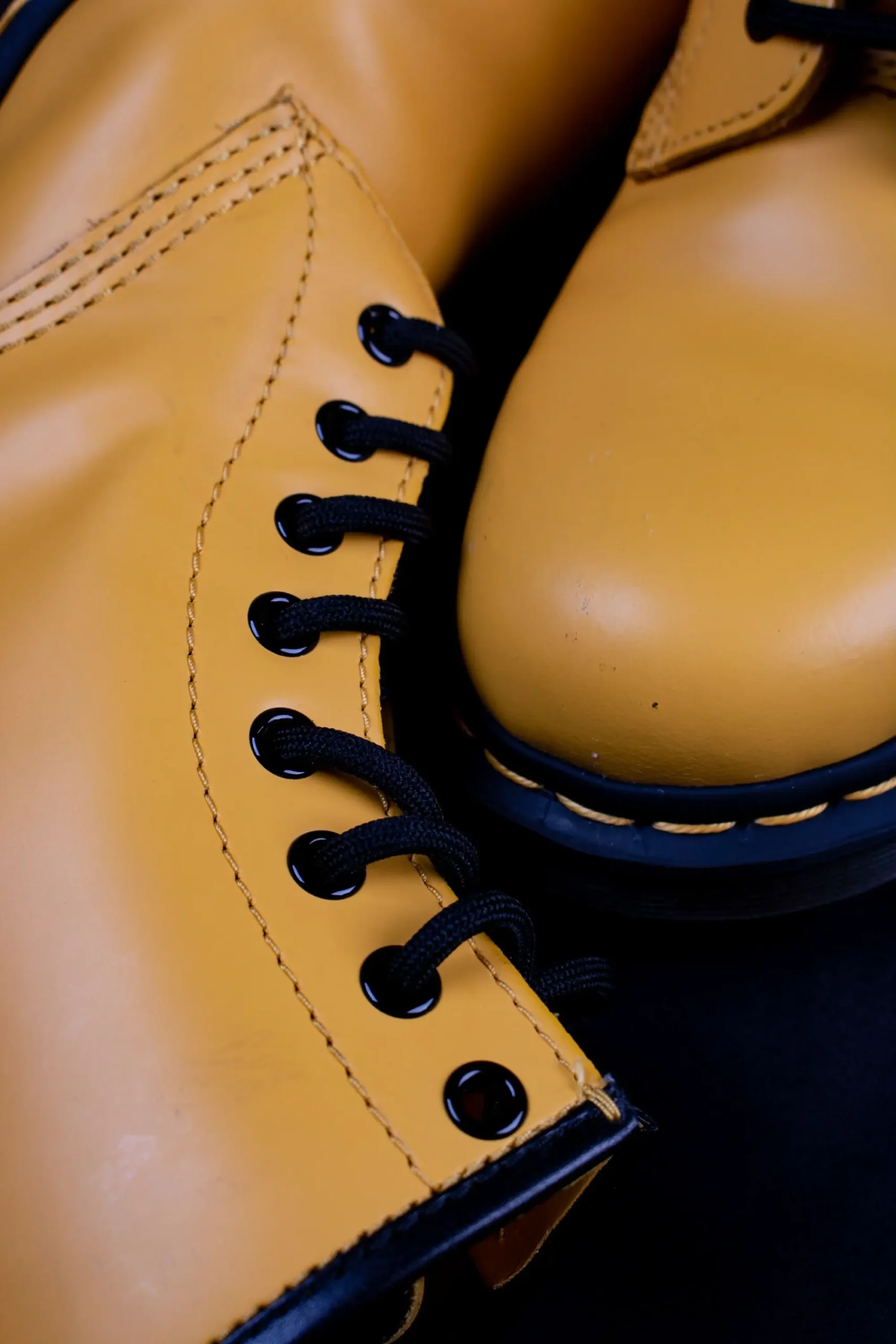 Close-up of worn brown leather work boots showing contrast stitching and creased uppers